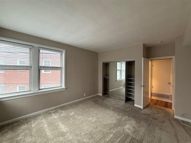 unfurnished bedroom with carpet flooring, visible vents, baseboards, and a closet