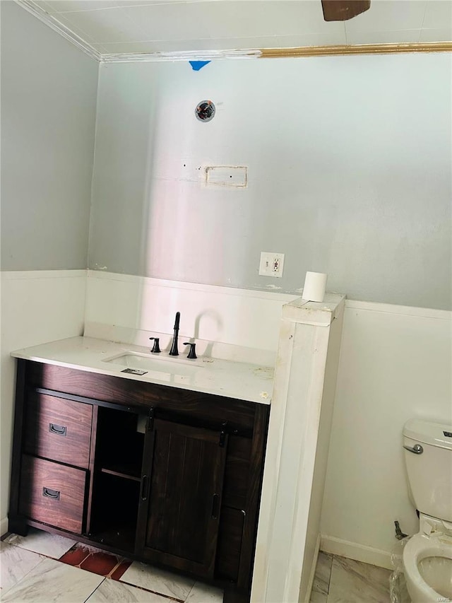 bathroom featuring toilet, vanity, and crown molding