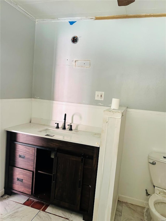 bathroom featuring toilet, vanity, and ornamental molding