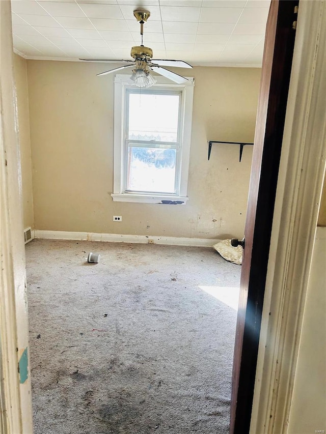 carpeted empty room with visible vents, baseboards, and a ceiling fan