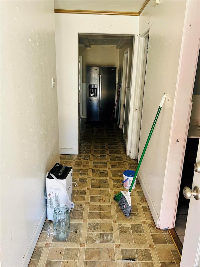 hall featuring brick floor and baseboards