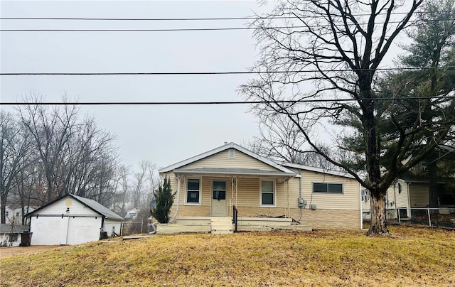 bungalow featuring an outbuilding, a porch, a front yard, and fence