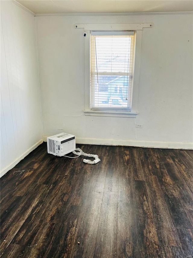 empty room featuring ornamental molding, baseboards, and wood-type flooring