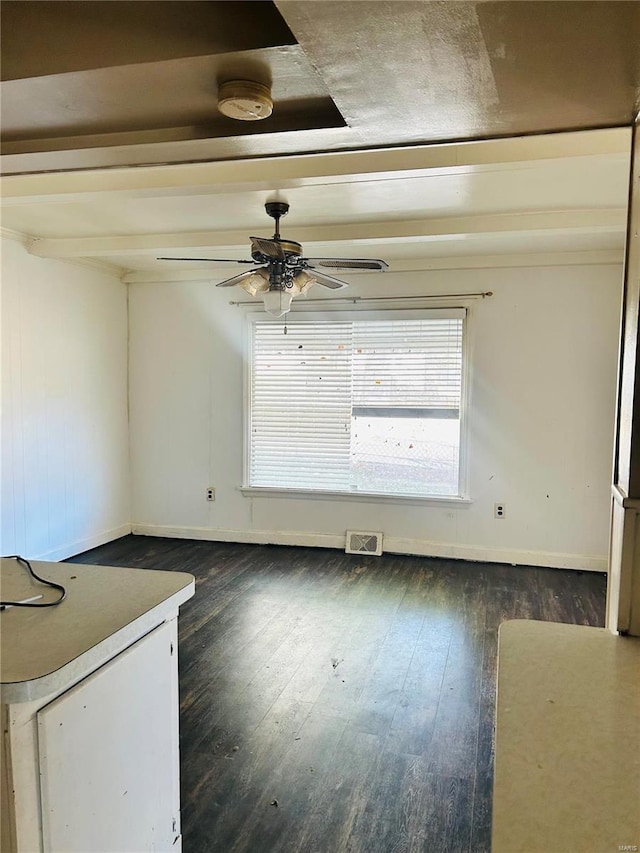 empty room featuring ceiling fan, visible vents, baseboards, and dark wood-style floors