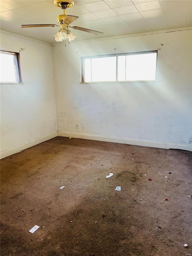 unfurnished room featuring crown molding, a ceiling fan, baseboards, and a wealth of natural light