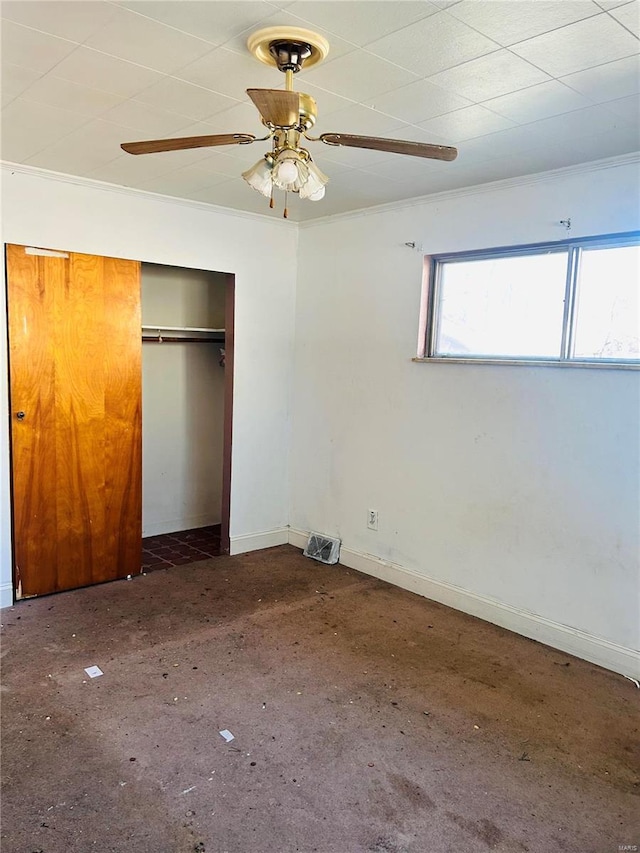 unfurnished bedroom with a closet, ceiling fan, crown molding, and baseboards