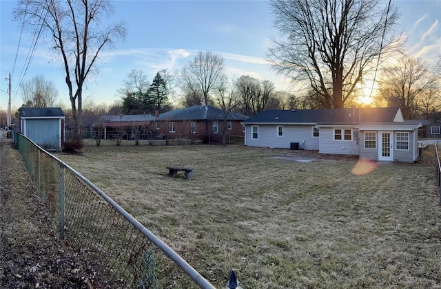 rear view of property featuring a shed, a lawn, an outdoor structure, and a fenced backyard