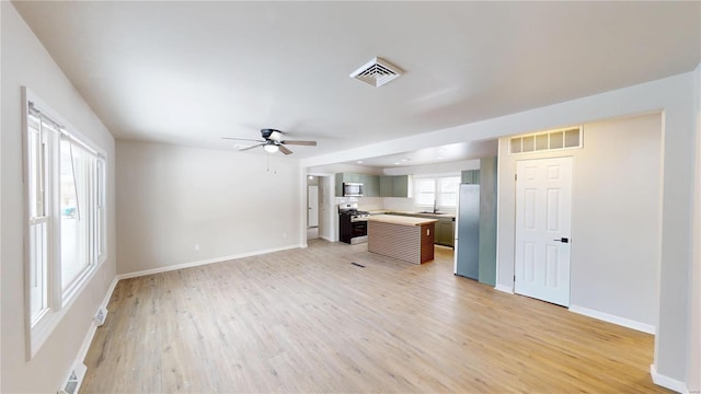 interior space featuring a ceiling fan, wood finished floors, visible vents, and baseboards