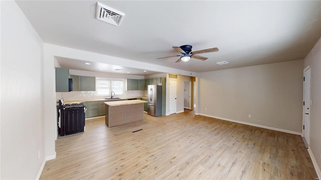 kitchen featuring visible vents, freestanding refrigerator, light countertops, light wood-type flooring, and a sink