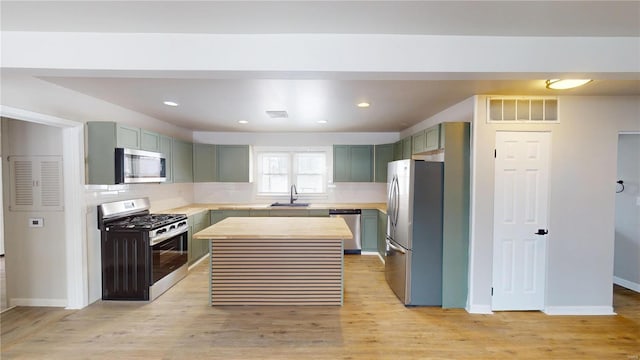 kitchen featuring a sink, visible vents, appliances with stainless steel finishes, light wood finished floors, and tasteful backsplash