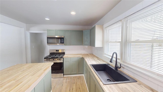 kitchen featuring recessed lighting, butcher block counters, appliances with stainless steel finishes, a sink, and light wood-type flooring