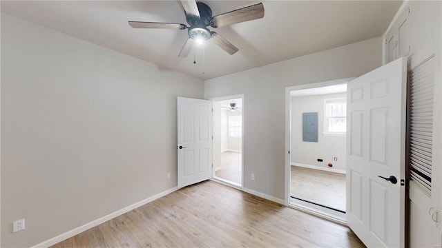 unfurnished bedroom with light wood finished floors, ceiling fan, electric panel, and baseboards