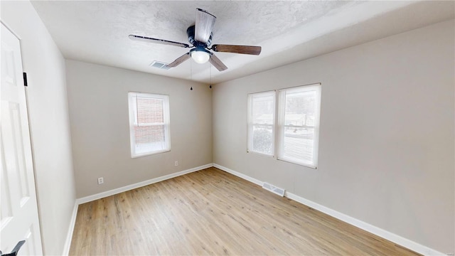 unfurnished room with light wood-style floors, baseboards, visible vents, and a ceiling fan