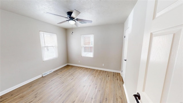 unfurnished room featuring a textured ceiling, a ceiling fan, baseboards, visible vents, and light wood-style floors