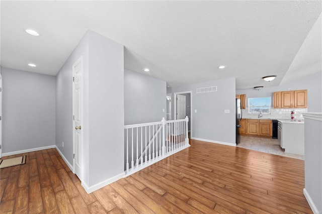 interior space featuring light wood-type flooring, a sink, visible vents, and baseboards