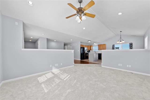 unfurnished living room with lofted ceiling, baseboards, and light colored carpet