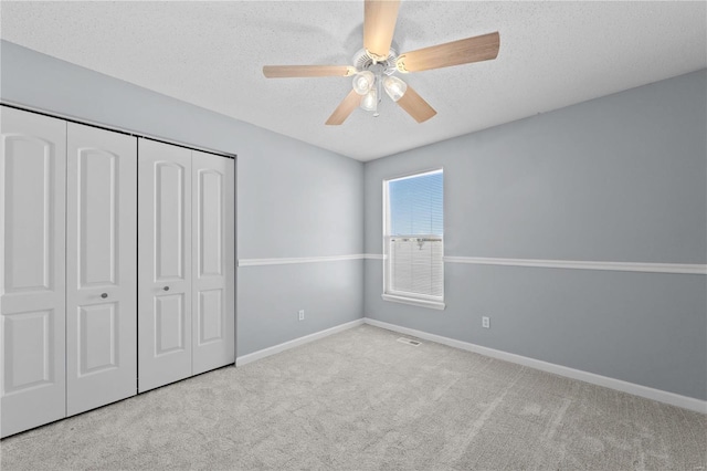 unfurnished bedroom with a textured ceiling, baseboards, a closet, and light colored carpet