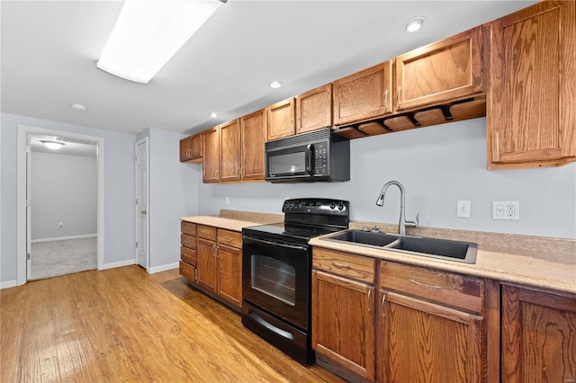 kitchen featuring black appliances, light countertops, a sink, and brown cabinetry