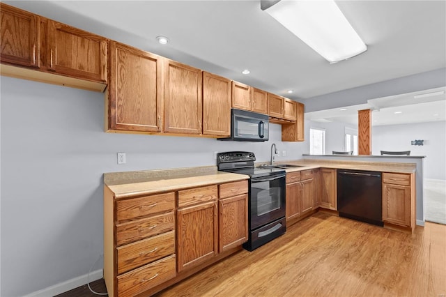 kitchen with brown cabinets, light wood-type flooring, light countertops, and black appliances