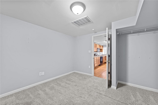 unfurnished bedroom featuring light carpet, baseboards, visible vents, and a closet