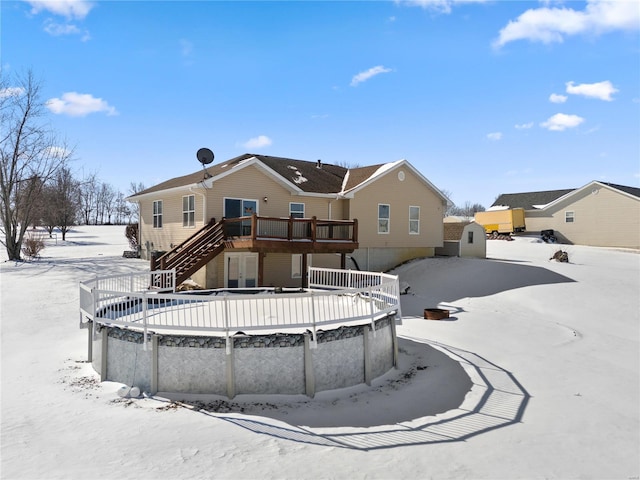 snow covered rear of property with a deck and stairs