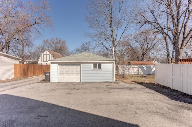 detached garage featuring fence and driveway