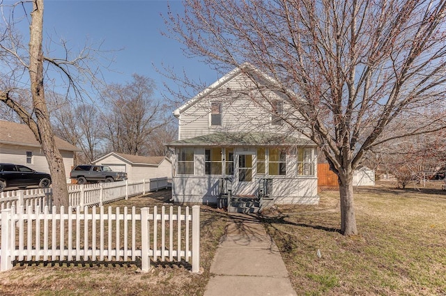 view of front facade featuring a front lawn, a fenced front yard, and a sunroom