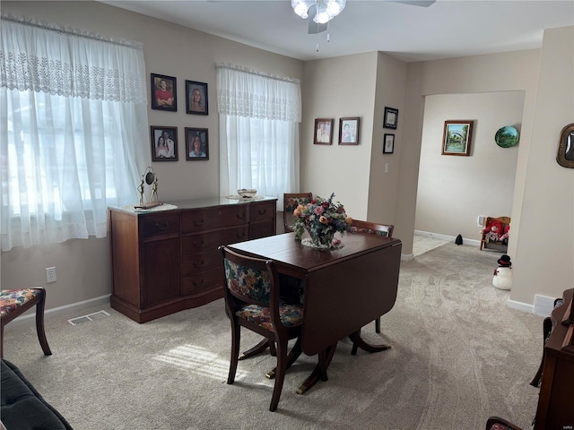 home office with light colored carpet, ceiling fan, visible vents, and baseboards