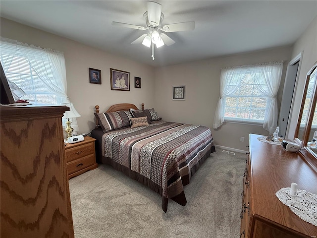 bedroom featuring baseboards, a ceiling fan, visible vents, and light colored carpet