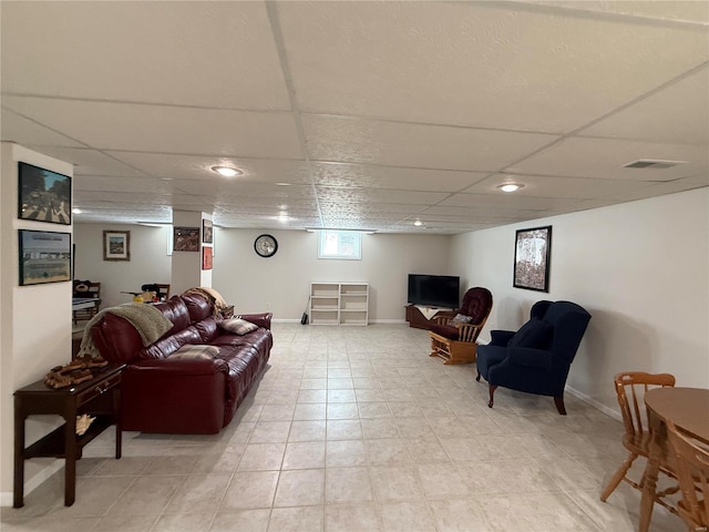 living room with a drop ceiling, visible vents, and baseboards