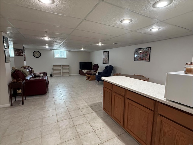 interior space with a drop ceiling, light tile patterned flooring, and baseboards