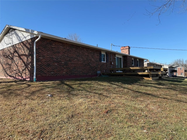 back of property featuring a yard and brick siding