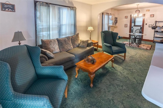 carpeted living room with arched walkways, a chandelier, and baseboards