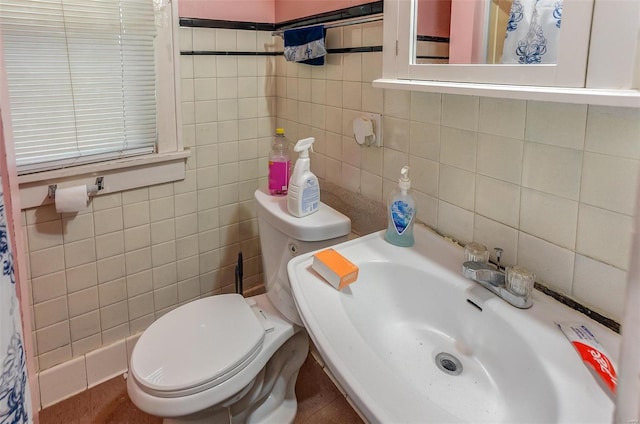 bathroom featuring a sink, tile walls, and toilet