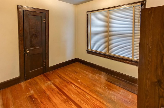 spare room with baseboards and wood finished floors