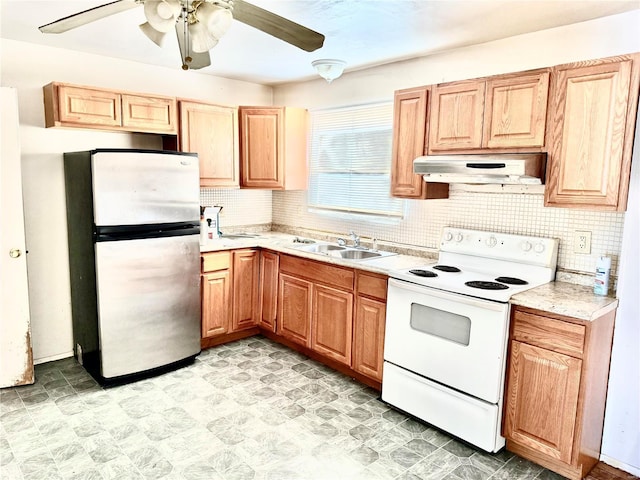 kitchen with under cabinet range hood, a sink, light countertops, freestanding refrigerator, and white range with electric cooktop