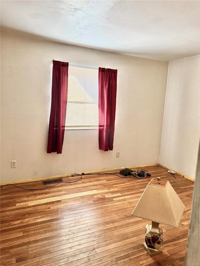 unfurnished room with visible vents and wood finished floors