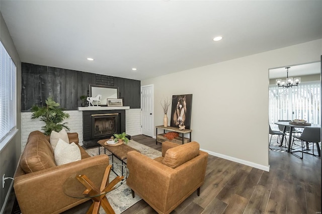 living room with baseboards, dark wood-style floors, a brick fireplace, a chandelier, and recessed lighting