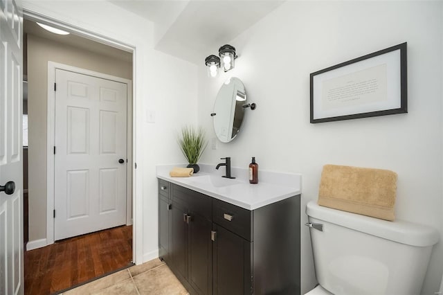 bathroom featuring toilet, tile patterned floors, baseboards, and vanity