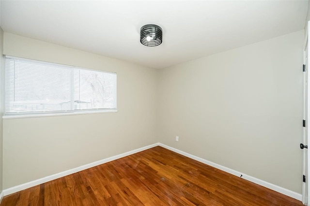 spare room with baseboards and wood finished floors