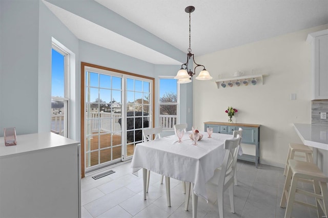 dining room with light tile patterned floors, baseboards, visible vents, and a notable chandelier