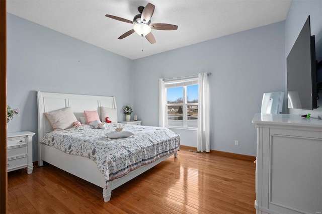 bedroom with ceiling fan, wood finished floors, and baseboards