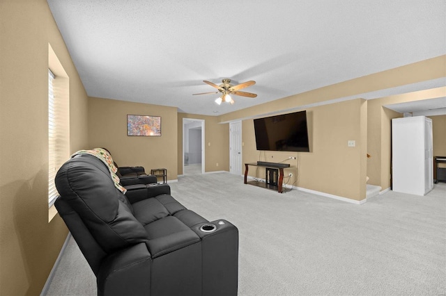 living room featuring a ceiling fan, light carpet, a textured ceiling, and baseboards