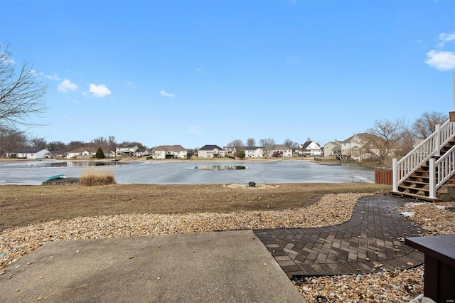 view of yard featuring stairs, a water view, and a residential view