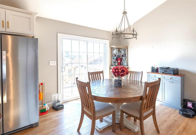 dining area featuring lofted ceiling, light wood-style floors, and an inviting chandelier