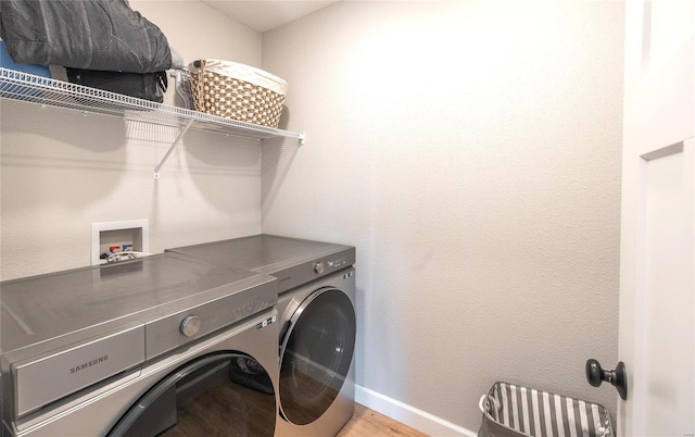 laundry room featuring laundry area, light wood-type flooring, washing machine and clothes dryer, and baseboards