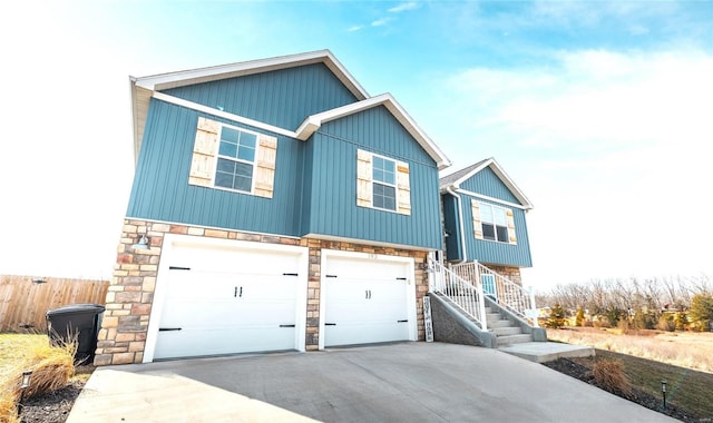 view of front of property featuring a garage, stone siding, and driveway