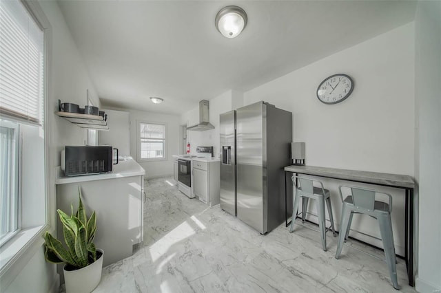 kitchen featuring stainless steel fridge, wall chimney exhaust hood, marble finish floor, light countertops, and white range with electric cooktop