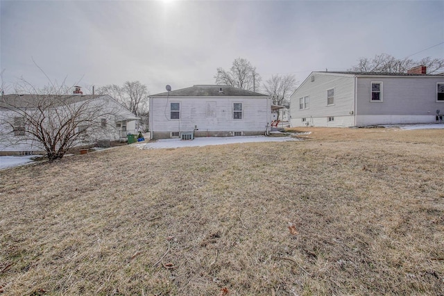 rear view of house featuring central AC unit and a lawn