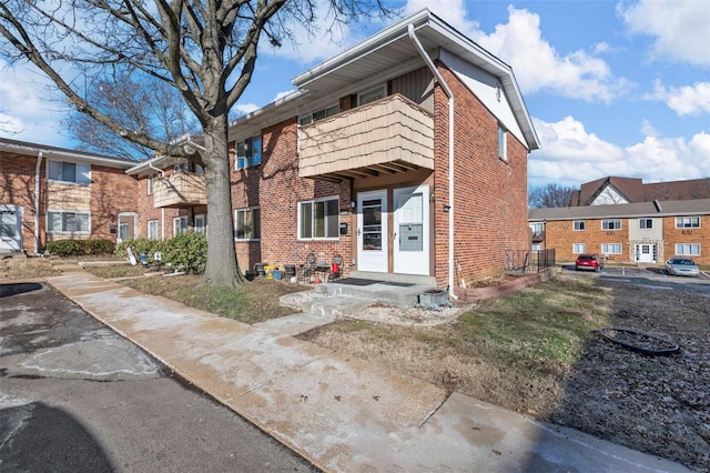 view of property featuring brick siding and a balcony